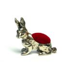 A SILVER NOVELTY RABBIT PIN CUSHION Having a red velvet cushion to back. (approx 3cm)