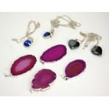 A COLLECTION OF FOUR WHITE METAL AND PURPLE AGATE PENDANTS oval form with hanging bale, together