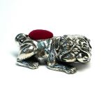 A SILVER NOVELTY BULLDOG PIN CUSHION Recumbent firm with red velvet cushion back. (approx 4cm)