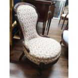 A VICTORIAN MAHOGANY FRAMED NURSING CHAIR With carved frame and floral upholstery, raised on