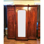 A VICTORIAN SOLID MAHOGANY BREAKFRONT TRIPPLE WARDROBE The central mirrored door enclosing slides