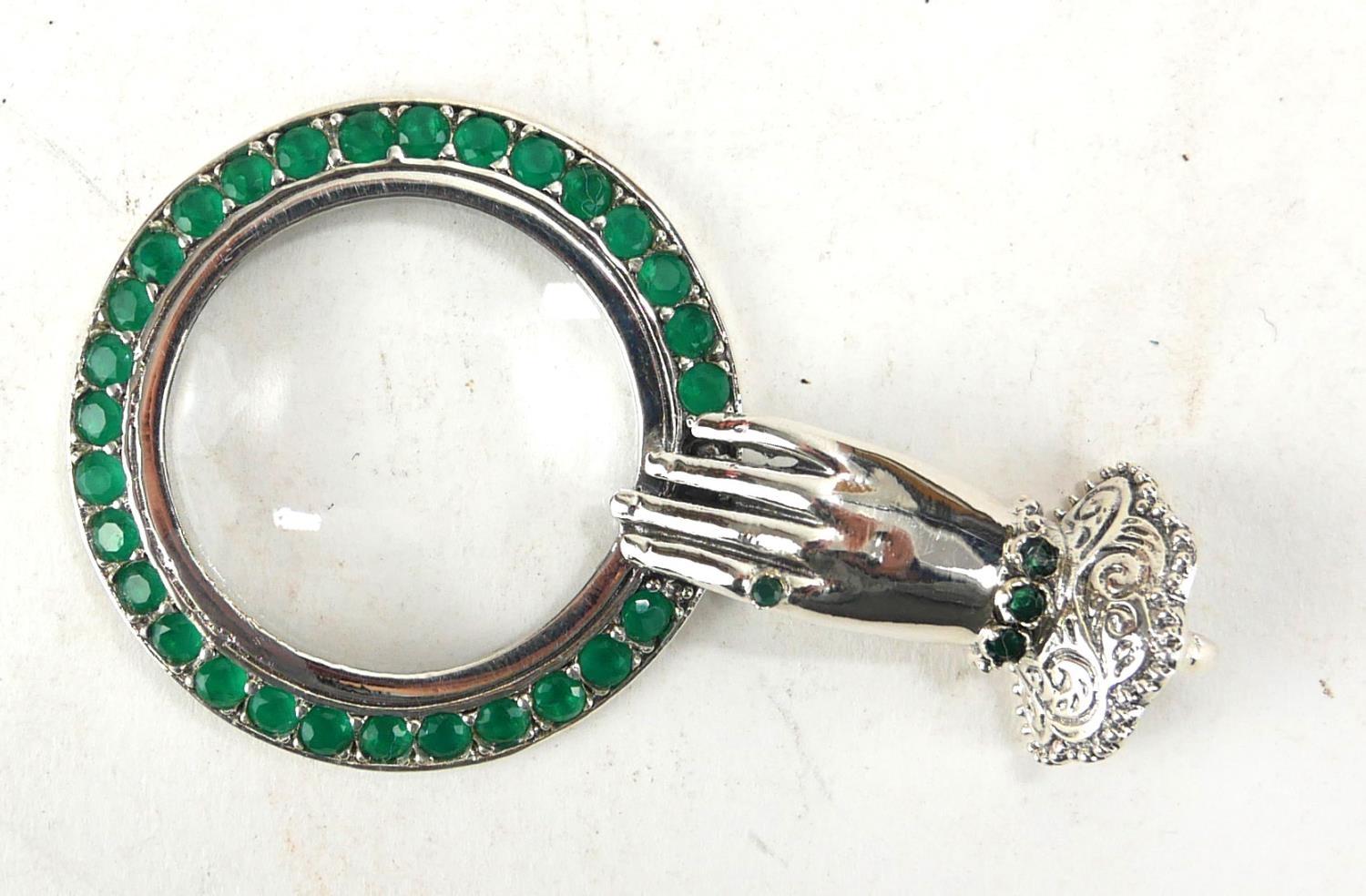 A SILVER AND PASTE SET 'HAND' NOVELTY MAGNIFYING GLASS Female hand with lace cuff and green glass