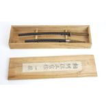 A PAIR OF JAPANESE MINIATURE SAMURAI SWORDS Having shagreen handles and black lacquer scabbards,