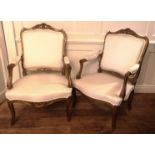 A PAIR OF FRENCH GILTWOOD FRAMED OPEN ARMCHAIRS Carved with cartouches and upholstered in a cream