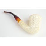 A CARVED MEERSCHAUM PIPE figured with a spread eagle and florets, with amber cheroot. (16cm)