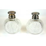 A PAIR OF VICTORIAN SILVER AND CUT GLASS PERFUME BOTTLES Having chased screw caps with internal