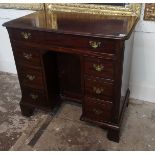 A GEORGIAN MAHOGANY KNEEHOLE DESK Fitted with an arrangement of seven drawers and central cupboard
