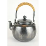 A JAPANESE WHITE METAL TEA KETTLE Having cane handle and matt finish textured body, bearing a four