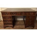 A REGENCY STYLE MAHOGANY DESK With brown tooled leather top above an arrangement of nine drawers. (