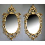 A PAIR OF GEORGE III CARVED GILTWOOD ROCOCO DESIGN OVAL MIRRORS, THE PLATE SURROUNDED BY FLOWER