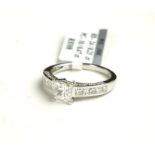 AN 18CT WHITE GOLD AND PRINCESS CUT DIAMOND RING Having a central princess cut stone with diamond