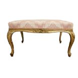 A LARGE 18TH CENTURY CARVED GILTWOOD FOOTSTOOL The upholstered seat above shell and foliage