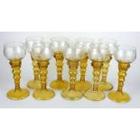 A SET OF NINE EARLY GERMAN AMBER GLASS WINE GOBLETS Having clear glass trumpets with acid etched