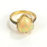 A CONTINENTAL SILVER GILT AND OPAL RING Having a pear cut stone with diamond chips to shoulders (