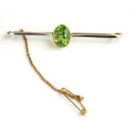 AN EARLY 20TH CENTURY YELLOW METAL AND PERIDOT BROOCH The oval cut stone on a plain yellow metal bar