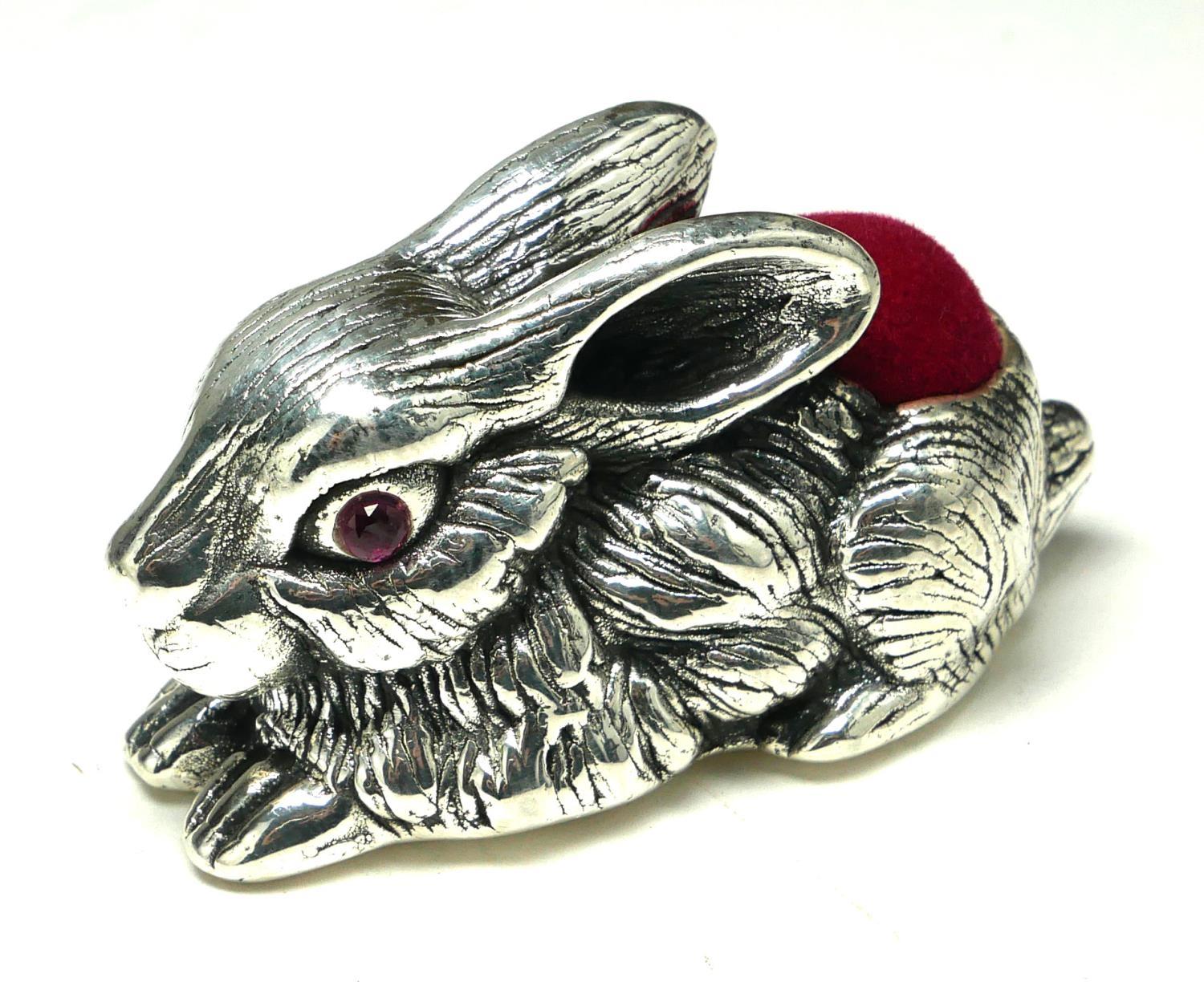 A STERLING SILVER NOVELTY 'RABBIT' PIN CUSHION Recumbent pose, with red velvet cushion. (approx