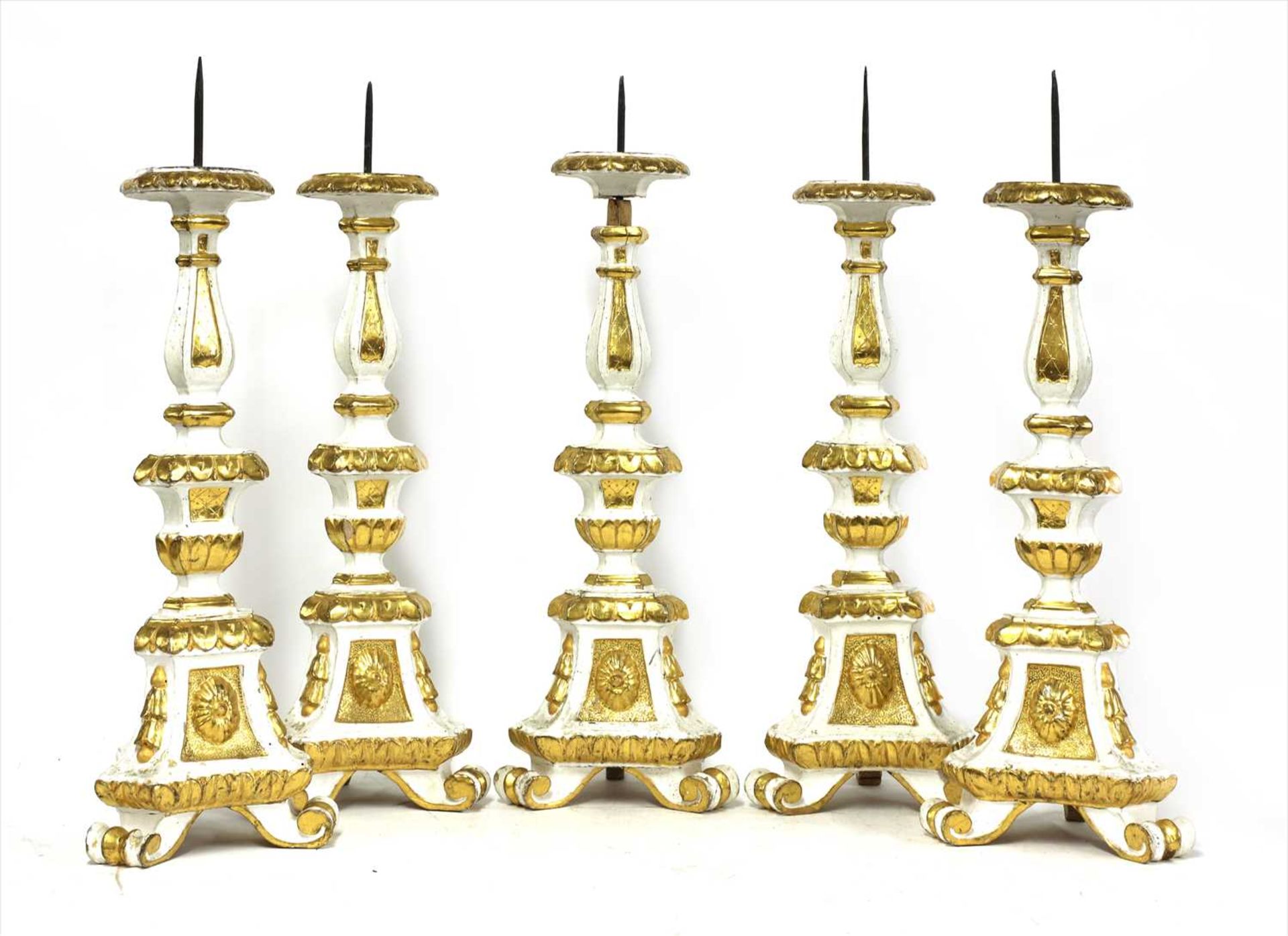 A set of five Italian carved and painted pine pricket candle stands