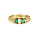 A gold five stone diamond and emerald ring