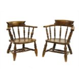 A pair of oak low spindle back elbow chairs