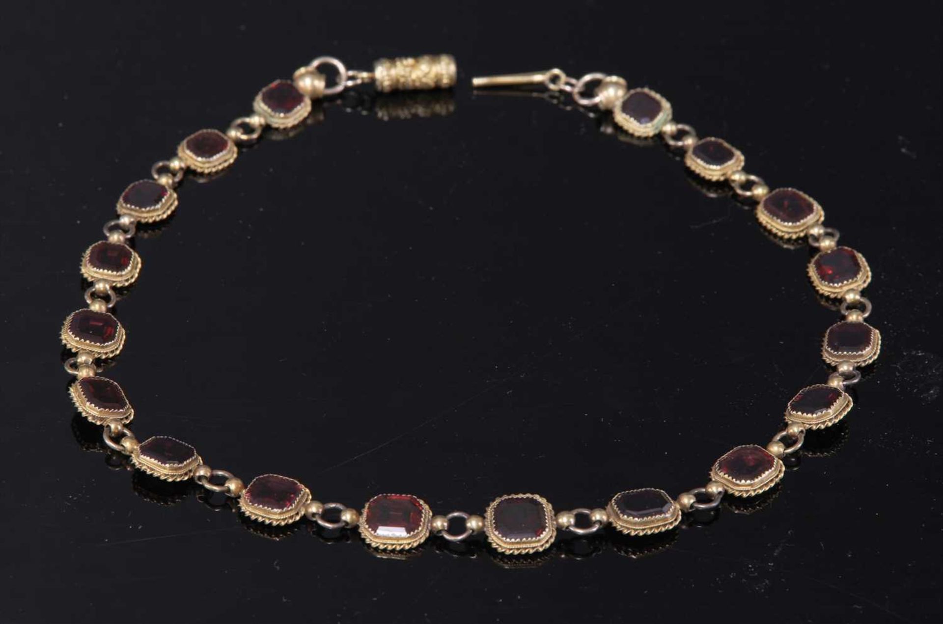 A gold garnet set rivière necklace,