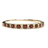 A gold garnet and diamond carved head-style hinged bangle,