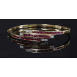 A gold ruby and diamond crossover hinged bangle,