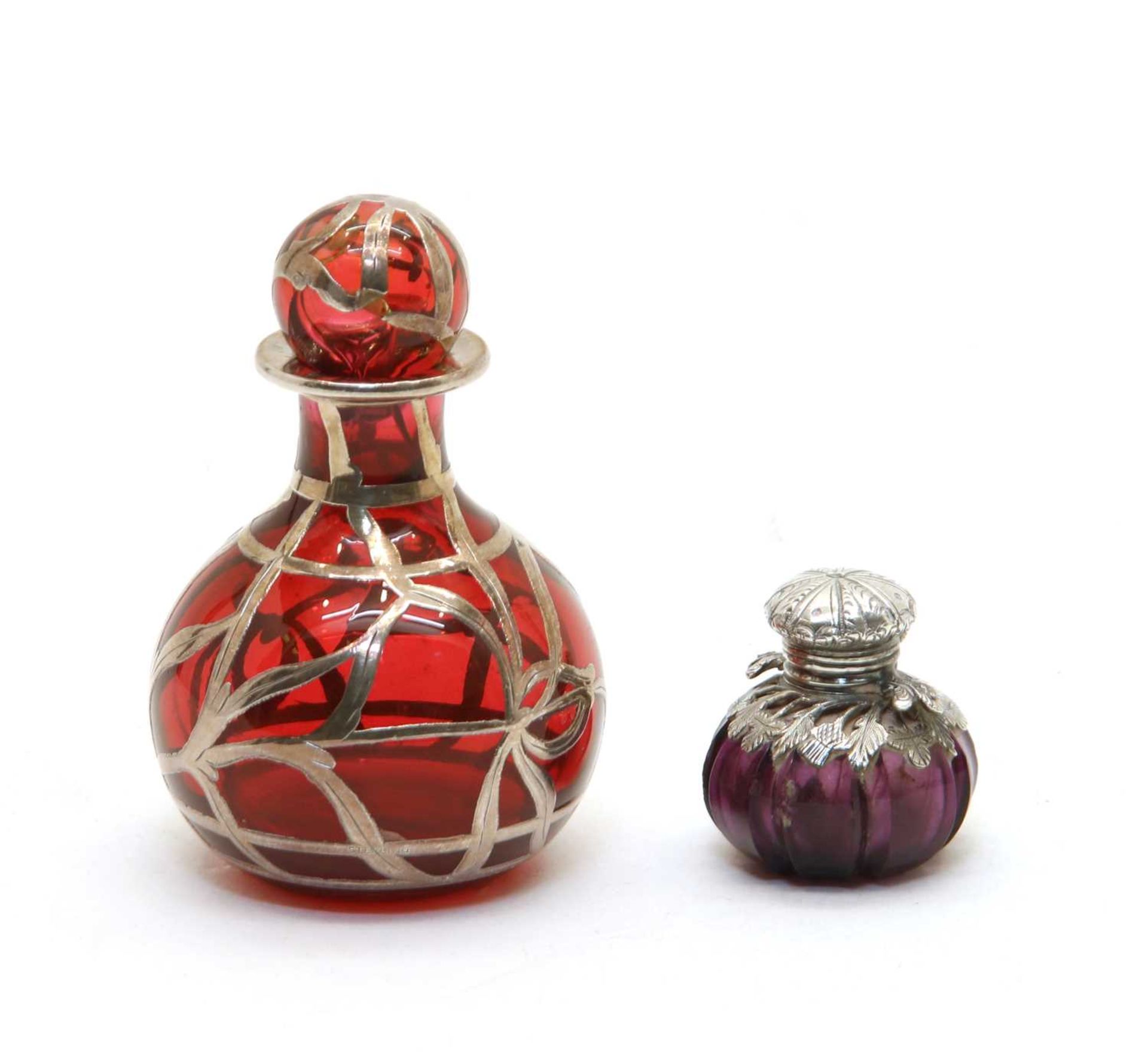 A small amethyst glass and white metal scent bottle of squat form,