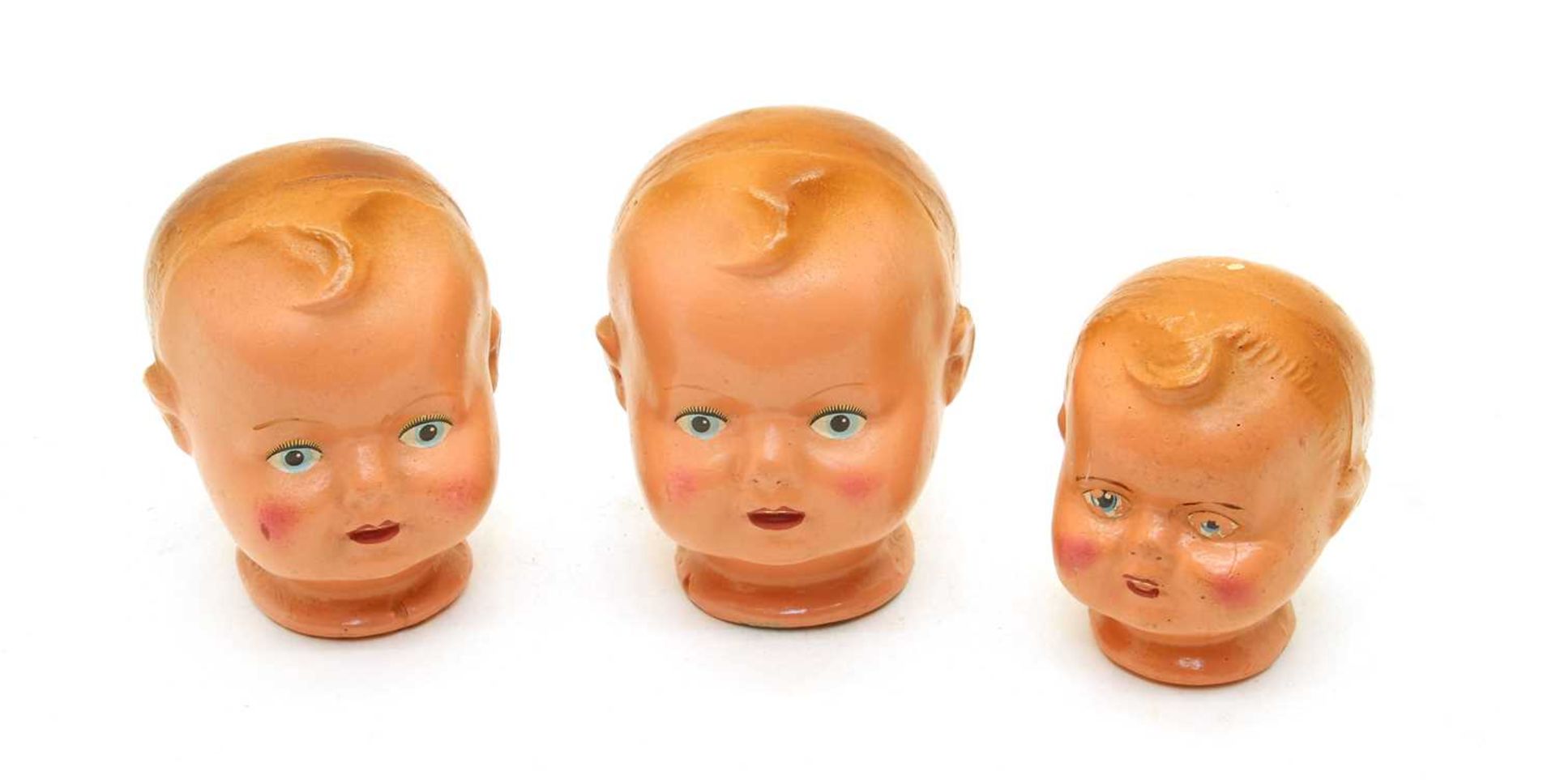 A collection of three pottery painted dolls heads