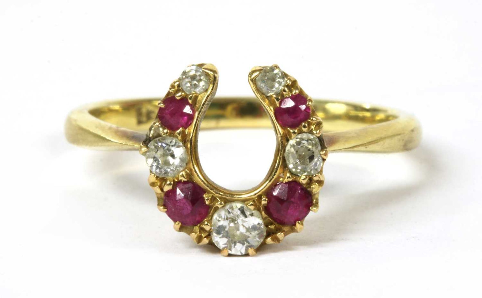 A gold diamond and ruby horseshoe ring,