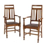 A pair of Arts and Crafts oak elbow chairs,