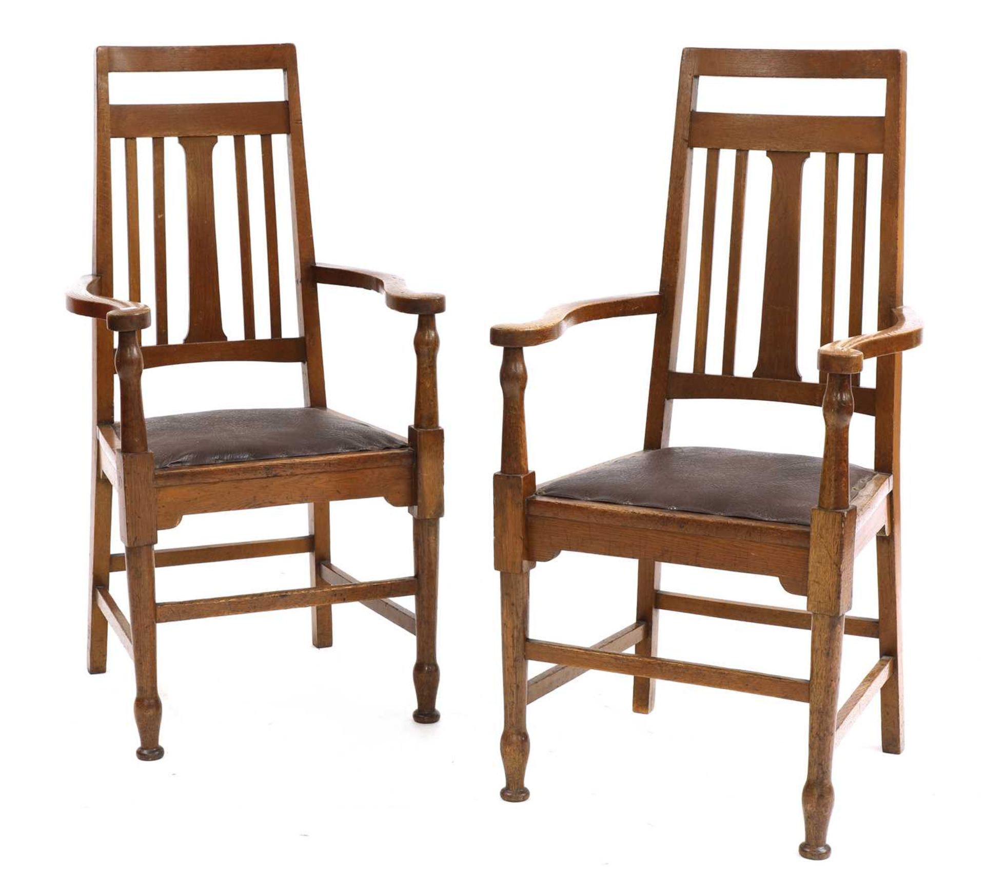 A pair of Arts and Crafts oak elbow chairs,