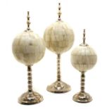 A set of three modern graduated bone orbs on chromium plated stands and finial mounts,