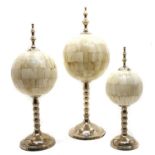 A set of three modern graduated bone orbs on chromium plated stands and finial mounts,