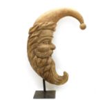 A carved wooden crescent 'Man in the Moon' on stand,