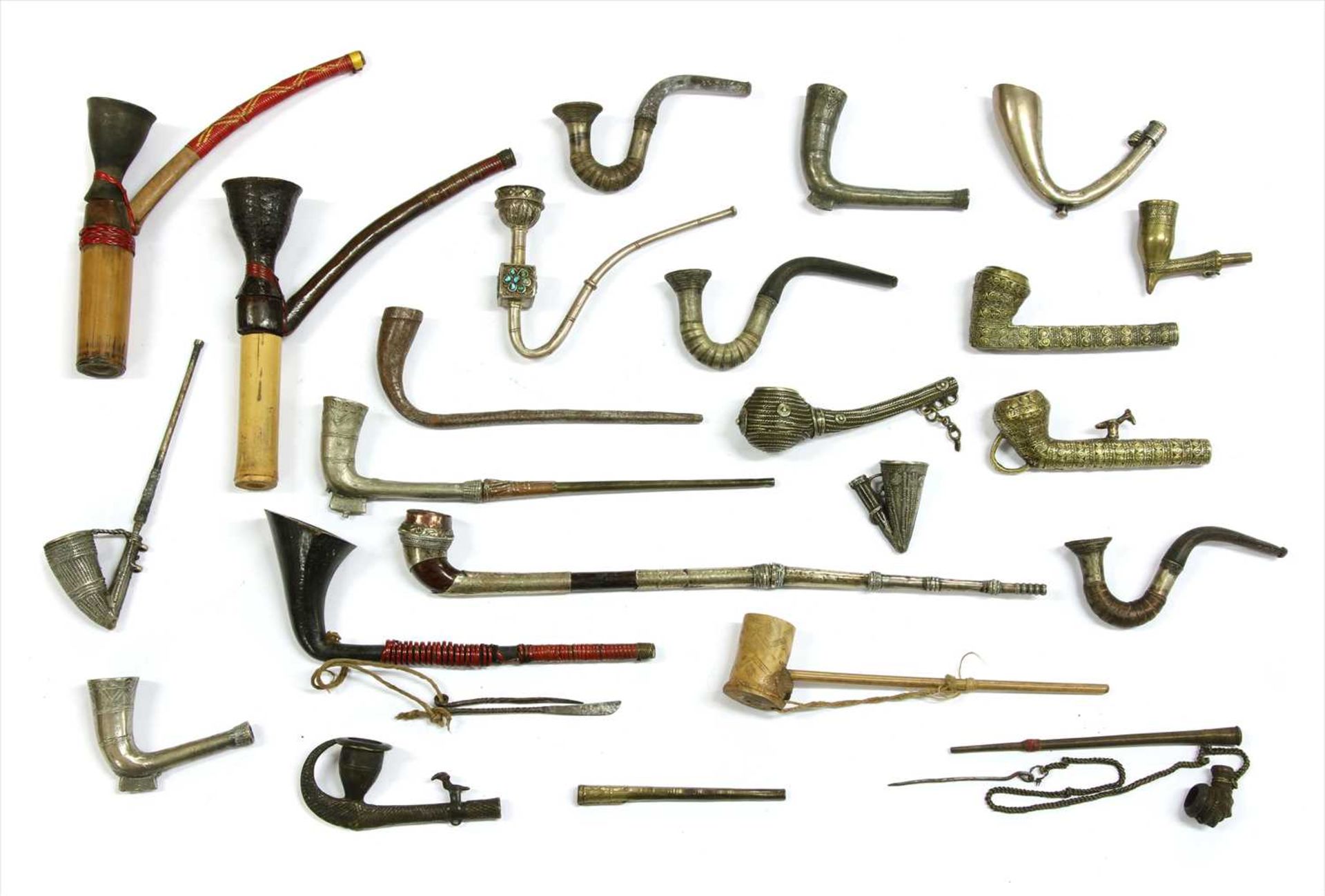 Twenty-two Indian metal and wood-mounted pipes,