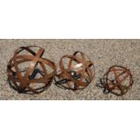 A graduated set of three contemporary rusted metal strapwork spheres,
