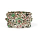 A silver hinged emerald, ruby and sapphire set bangle,