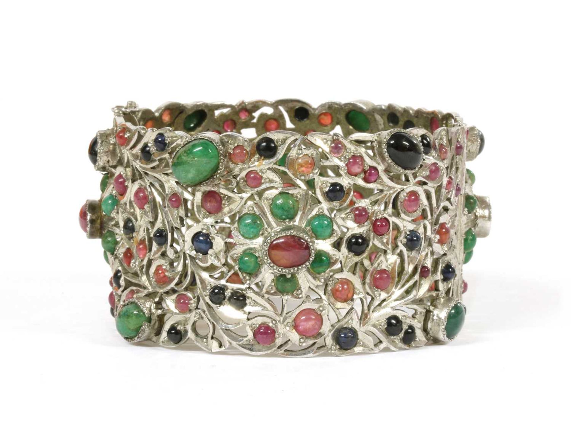 A silver hinged emerald, ruby and sapphire set bangle,