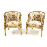 A pair of empire style carved and giltwood barrel back armchairs,