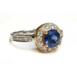 An 18ct rose and white gold sapphire and diamond halo cluster ring,