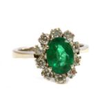 An 18ct white gold emerald and diamond oval cluster ring,