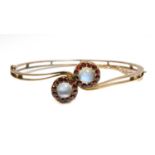 A gold moonstone and garnet cluster crossover bangle,