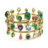 An 18ct gold emerald, aquamarine, amethyst, tourmaline, peridot and diamond hinged bangle,