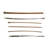 Three military malacca canes and two leather and braided whips