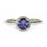 A white gold tanzanite and diamond halo cluster ring,