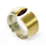 A silver and gold garnet torque ring by Manu Schmuck,