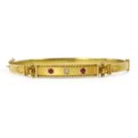 A gold diamond and ruby set oval hinged bangle,