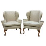 A closely matched pair of George III-style wing back armchairs,