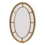 A carved giltwood and gesso oval wall mirror,