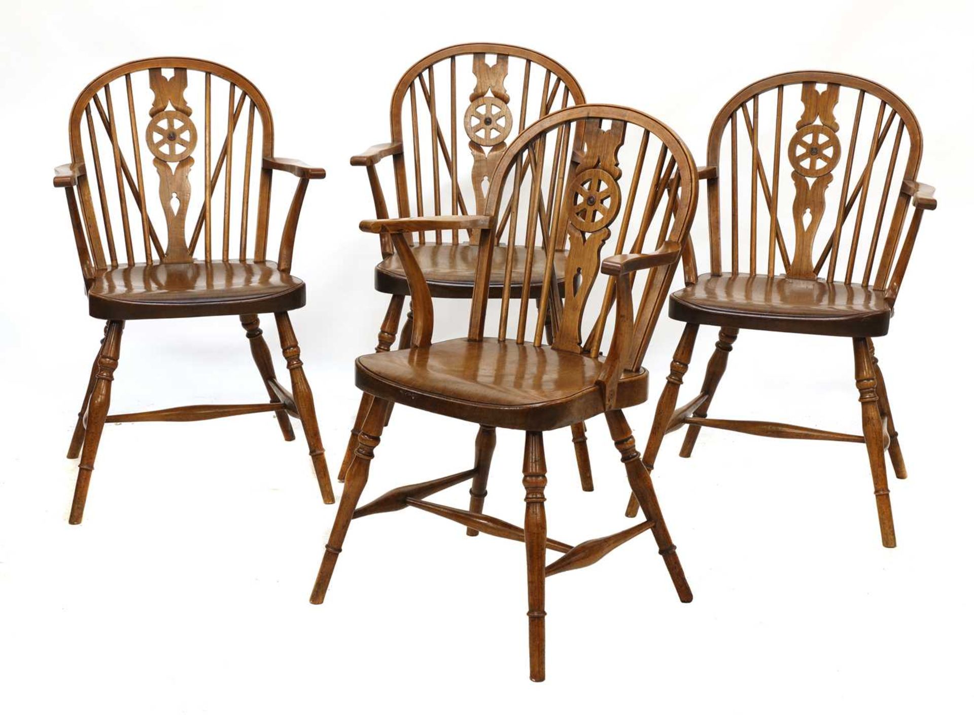 A set of four walnut and fruitwood wheel back Windsor chairs,